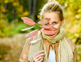 Blonde attraktive Frau versteckt sich hinter einem Herbstblatt