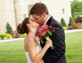 Hochzeitspaar küsst sich vor einer Kirche