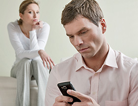 Ein Mann schreibt in Gegenwart seiner Frau eine SMS an seine Exfreundin.