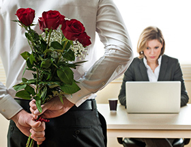 Mann hält Rosen hinter seinem Rücken versteckt. er will sie seiner Arbeitskollegin schenken