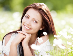 Frau liegt auf Blumenwiese und lächelt in Kamera