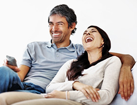Mann und Frau sitzen auf der Couch und lachen